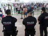 Agentes de los Mossos d'Esquadra controlan de los accesos a las puertas de embarque en el Aeropuerto de El Prat este sábado.