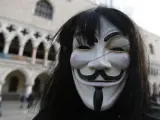 Una persona tapa su rostro con la famosa máscara del movimiento Anonymous, en el centro de la plaza de San Marcos de Venecia (Italia).