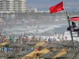 Un socorrista vigila la playa de la Malvarrosa (Valencia) a la que ha acudido un gran número de personas a pesar de la inestabilidad climática, señalada con la bandera roja.