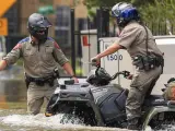 Varios oficiales en un barrio inundado por la crecida del río Buffalo Bayou en Houston.