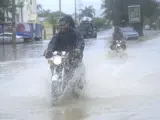 Un motociclista pasa por una calle inundada en Villa Vásquez, República Dominicana.