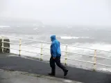 Un hombre camina junto al fuerte oleaje en la costa del Condado de Clare (Irlanda).