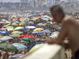 Un hombre observa la playa de la Malvarrosa abarrotada por miles de ba&ntilde;istas.