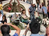 Varios turistas se fotografían junto al popular dragón de trencadís del Park Güell de Barcelona.