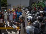 Un grupo de personas protesta frente a miembros de la Policía Nacional Bolivariana (PNB) por la escasez de alimentos y la falta de gas doméstico y agua.