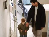 Un padre entra en casa con su hijo.