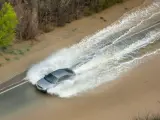 Un coche circula por la recta de Arguedas anegada de agua