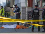 Oficiales de la policía de Toronto vigilan frente a un cuerpo cubierto después del atropello masivo en una de las calles del centro de la ciudad.