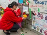Una persona deposita flores en el memorial por las víctimas del atropello múltiple en Toronto, que dejó al menos 10 muertos y 15 heridos.