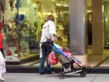 Una mujer mira un escaparate con su hija en una silla de paseo.