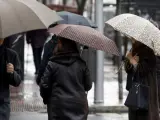 Varias personas caminan con paraguas por la calle en un día lluvioso.