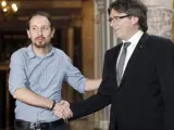 El presidente de la Generalitat, Carles Puigdemont (d), saluda al líder de Podemos, Pablo Iglesias.