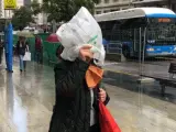 Una mujer se protege de la lluvia con una bolsa en pleno centro de Madrid, este mes de junio.
