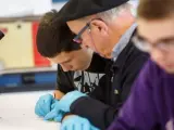 Un abuelo y su nieto realizan un experimento en el Laboratorio de la UPNA.