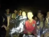 Un miembro de las fuerzas especiales de la Marina tailandesa, con los niños atrapados en la cueva Tham Luang, en Tailandia, en una captura de vídeo.