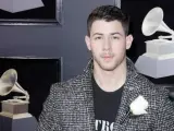 Nick Jonas posa en la alfombra roja de la 60 edición de los Premios Grammy luciendo una rosa blanca en apoyo del movimiento #MeToo contra el acoso sexual.