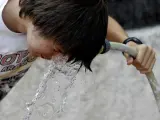 Un chico se refresca con agua.