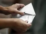 Un ciudadano introduce su papeleta electoral en un sobre.