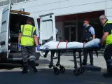 Miembros del servicio judicial retiran el cadáver del hombre que ha sido abatido al intentar acceder a la comisaría de los Mossos de Cornellà con un cuchillo.