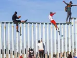 Integrantes de la caravana de centroamericanos escalan el muro fronterizo con EE UU en Tijuana, México.
