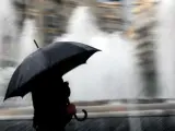 Una persona se resguarda bajo un paraguas en el centro de Valencia.