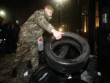 Un protestante coloca neumáticos durante una concentración cerca de la embajada rusa en Kiev (Ucrania).