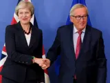 La primera ministra británica saluda al presidente de la Comisión Europea, Jean-Claude Juncker.