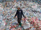Un trabajador camina entre montañas de botellas de plástico en una planta de reciclaje de Samut Sakhon, afueras de Bangkok, Tailandia.