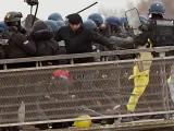 El excampeón de boxeo francés Christophe Dettinger (c-vestido con gorro negro) patea a un miembro del Cuerpo de Gendarmería durante una manifestación de los 'chalecos amarillos' en París el 5 de enero.