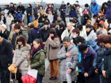 Varias personas guardan un minuto de silencio este lunes en memoria de las víctimas del terremoto y posterior tsunami que causó más de 18.000 muertos.