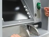 Una persona saca dinero de un cajero automático, en una imagen de archivo.