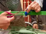 El presidente de una mesa corta el precinto de una urna antes del inicio del recuento de votos en un colegio electoral de Sevilla durante la jornada electoral de Andaluc&iacute;a.