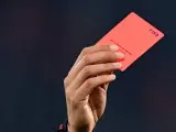Un árbitro saca una tarjeta roja.