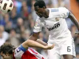 Emmanuele Adebayor, delantero del Real Madrid, remata de cabeza ante Iván Hernández, defensa del Sporting.