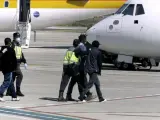 Agentes de la Policía Nacional trasladan hasta el avión a un grupo de inmigrantes desde Melilla a la península (imagen de archivo). /EFE