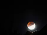 La Luna eclipsada asoma por la montaña de Las Tricias, en el municipio de Garafía, al norte de la isla de La Palma.