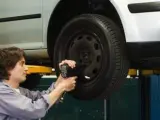 Un trabajador cambiando las ruedas a un coche en un taller mecánico.
