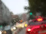 Una calle con retenciones por la lluvia, vista desde el interior de un coche con los cristales empapados.