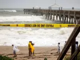 Varias personas se fotografían en una playa, con el mar rizado, junto al muelle de Juno Beach, Florida (EE UU), antes de la llegada del huracán Dorian.