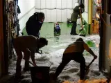 Varias personas limpian el garaje de una vivienda en Viana de Cega, repleto de granizo, tras una fuerte tromba de agua caída en la provincia de Valladolid.