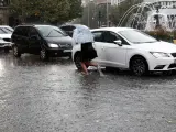 Una joven cruza una calle inundada de Pamplona tras la caída de una tromba de agua.