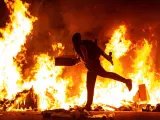 Un participante en las revueltas de Barcelona alimenta el fuego con cartones.