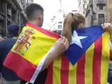 Una pareja, él con la bandera de España y ella con una estelada, se abrazan en Barcelona.