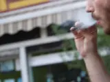 Un joven fuma a través de un cigarrillo electrónico