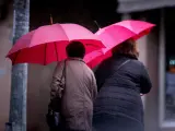 Dos mujeres ser protegen de la lluvia en las calles de Ourense.
