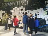 Un grupo de niños busca sus cartas en el mural que Madres por el Clima ha creado en la COP25.