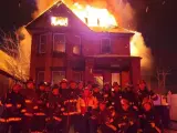 Un grupo de bomberos posa ante una casa en llamas en la ciudad estadounidense de Detroit.