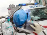 Personal médico con protección para evitar contagios, junto a una ambulancia en un hospital de Wuhan, China.