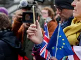 Una mujer utiliza su teléfono móvil en una protesta contra el brexit.