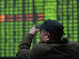 Un inversor bursátil se sienta frente a una pantalla de la Bolsa en Hangzhou, China,